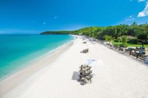 Sandals Grande Antigua - All Inclusive Resort and Spa - Couples Only في سانت جونز: شاطئ به كراسي ومظلات والمحيط