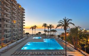 a swimming pool with palm trees and a building at Apto a pie de playa con vistas increíbles! in Torremolinos