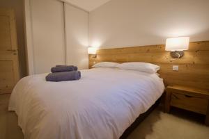 a bedroom with a white bed with a wooden headboard at Django in Les Gets