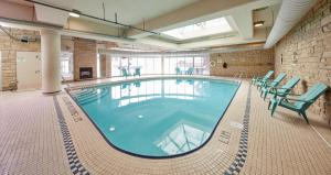 a large swimming pool with green chairs in a building at The Falls Hotel & Inn in Niagara Falls