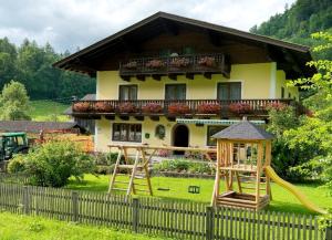 une maison avec une aire de jeux en face d'une clôture dans l'établissement Hinterkellaubauer, à Kuchl