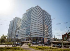 トムスクにあるКвартира на Большой Подгорнойの車が目の前に停まった高い建物