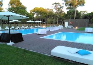 a swimming pool with tables and chairs and an umbrella at INATEL Caparica in Costa da Caparica