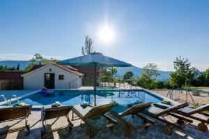 a swimming pool with chairs and an umbrella at Villa Mlin in Gruda