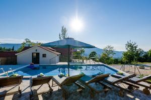 una piscina con sillas y sombrilla en Villa Mlin, en Gruda