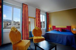 a bedroom with a bed and two chairs and a window at The Ambassador in Geneva