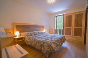 a bedroom with a bed and a desk and a window at GH Hotel Fratazza in San Martino di Castrozza