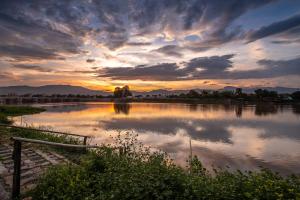 een grote hoeveelheid water met een zonsondergang op de achtergrond bij Doi Inthanon Riverside resort in Chom Thong