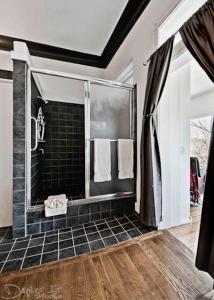 a bathroom with a walk in shower with black tile at New Orleans Hotel Eureka Springs in Eureka Springs