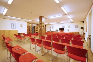 a conference room with red chairs and a podium at GH Hotel Fratazza in San Martino di Castrozza