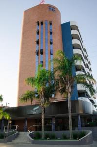 a building with palm trees in front of it at Classe Apart Hotel in Feira de Santana