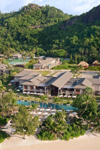 a house with trees and palm trees in the distance at Kempinski Seychelles Resort in Baie Lazare Mahé