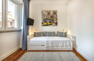 リスボンにあるMarquês de Pombal Metropolitan Flatの白いベッドと壁に絵画が飾られたベッドルーム1室
