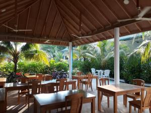 un restaurant avec des tables en bois, des chaises et des arbres dans l'établissement Sunrise Inn, à Thoddoo