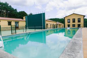 une piscine avec de l'eau bleue devant un immeuble dans l'établissement Centro Río Lobos, à Hontoria del Pinar
