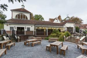 a patio with wooden benches and a building at The Conningbrook Hotel in Ashford