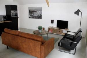 a living room with a brown couch and two chairs at ons huusie in Noord-Sleen