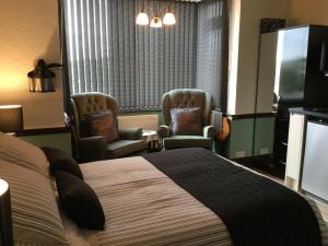 a hotel room with a bed and two chairs at Southcroft in Bridport