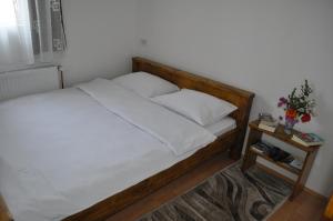 a bed with a wooden frame and white sheets and pillows at Green House in Kolašin