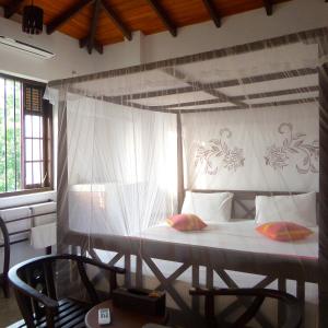 - une chambre avec un lit et une moustiquaire dans l'établissement Lagoon Boutique Hotel, à Tangalle