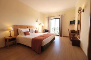 a hotel room with a large bed and a window at Quinta dos Poetas Nature Hotel & Apartments in Olhão
