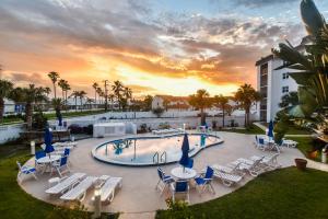 a pool with chairs and tables and a sunset at Daytona Beach Shores Condos in Daytona Beach Shores