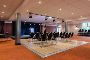 einen Konferenzraum mit Stühlen und eine Bühne im Hintergrund in der Unterkunft Hôtel du Béryl, Lons-le-Saunier in Lons-le-Saunier