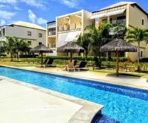 a swimming pool in front of a building with umbrellas at Apartamento Alto Padrão 3 quartos Iberostate Praia do Forte in Praia do Forte