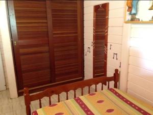 a bedroom with a bed and some wooden shutters at Chambre à louer chez l'habitant dans Villa Créole Authentique et en Bois in Trois-Rivières