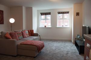 a living room with a couch and two windows at Bolton Executive Apartment in Bolton