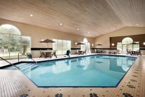 a large swimming pool in a hotel with tables and chairs at Country Inn & Suites by Radisson, Des Moines West, IA in Clive