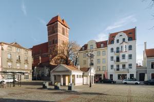 un bâtiment avec une tour d'horloge dans une ville dans l'établissement Apartamenty Europa, à Toruń