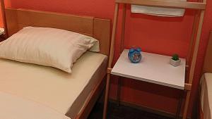 a bedroom with a bed and a nightstand with a clock on it at Apartmani 077 in Drvar