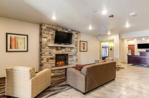 a living room with two chairs and a fireplace at Cobblestone Hotel & Suites - Gering/Scottsbluff in Gering