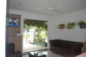 ein Wohnzimmer mit einem Sofa und einem Flachbild-TV in der Unterkunft Hotel Calarca Plus in Montería