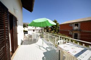 奧瑞比克的住宿－Rooms Smilje - good location & parking，阳台的绿色遮阳伞,配有桌椅
