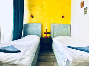 two beds in a room with a yellow wall at City Center Loft by Happy Place in Tbilisi City