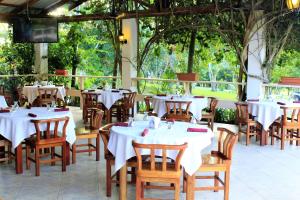 um restaurante com mesas brancas, cadeiras e árvores em The Log Cab-Inn em San Ignacio