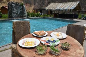 a table with plates of food next to a swimming pool at Oasis Paraiso Ecolodge in Cabanaconde