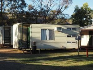 een kleine witte caravan geparkeerd in een tuin bij Heritage Caravan Park in Alice Springs