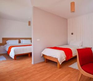 a bedroom with two beds and a red chair at Hotel Ilaia in Punta Arenas