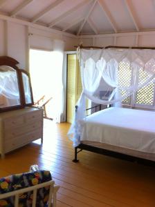 a bedroom with a white bed and a dresser at Treehouse Cottage in Five Islands Village
