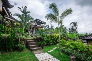 a garden with stairs and palm trees in front of a house at Arta Nadi Villa in Sidemen