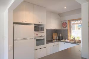 a kitchen with white cabinets and a stainless steel refrigerator at The Lodges in Queenstown