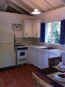 a kitchen with white cabinets and a white stove top oven at Treehouse Cottage in Five Islands Village