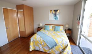 Sumner Bay Motel في كرايستشيرش: غرفة نوم بسرير وبطانية صفراء وزرقاء