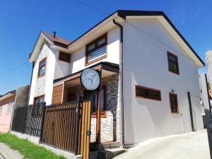 Una casa blanca con un reloj al costado. en Abriga Bed and Breakfast, en Coyhaique