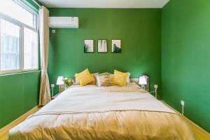 een groene slaapkamer met een groot bed met gele kussens bij Xi'an Lianhu·Longshou Business Circle· Locals Apartment 00154940 in Xi'an