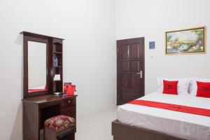 a bedroom with a bed and a dresser and a mirror at RedDoorz near Banyuwangi Baru Station in Ketapang