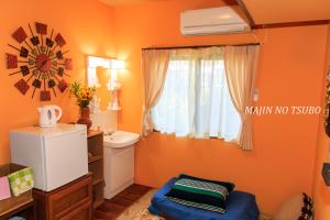 a small bathroom with orange walls and a window at Majin No Tsubo in Nakijin
